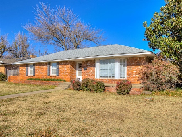 single story home with a front lawn, a chimney, brick siding, and a shingled roof