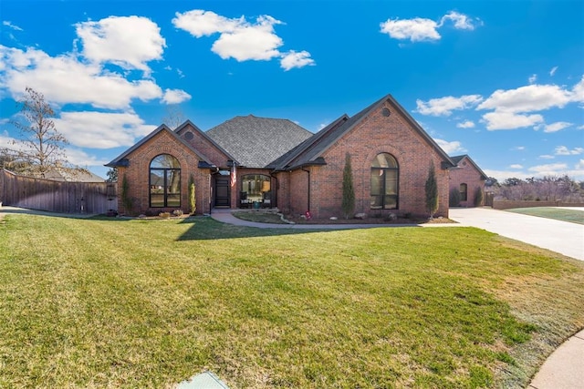 view of front of house featuring brick siding, concrete driveway, a front yard, and fence