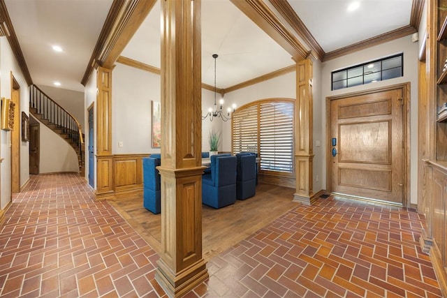 entrance foyer with wainscoting, stairs, brick floor, and decorative columns