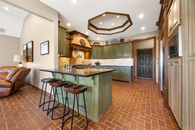 kitchen with green cabinetry, a peninsula, recessed lighting, decorative backsplash, and dark countertops