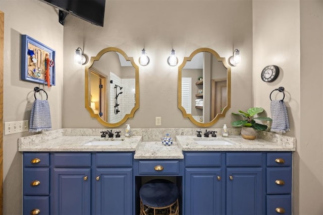 bathroom with double vanity, tiled shower, and a sink