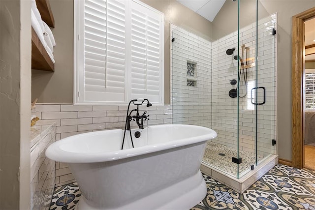 bathroom featuring a shower stall, a soaking tub, and tile walls