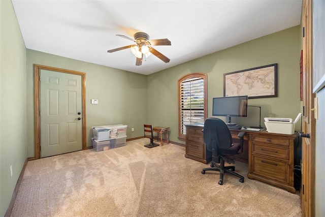 carpeted office space featuring baseboards and ceiling fan