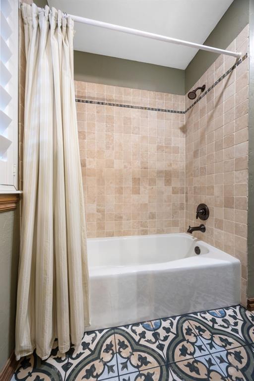 bathroom with shower / bath combo with shower curtain and tile patterned flooring