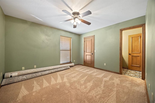 carpeted spare room with a ceiling fan and baseboards