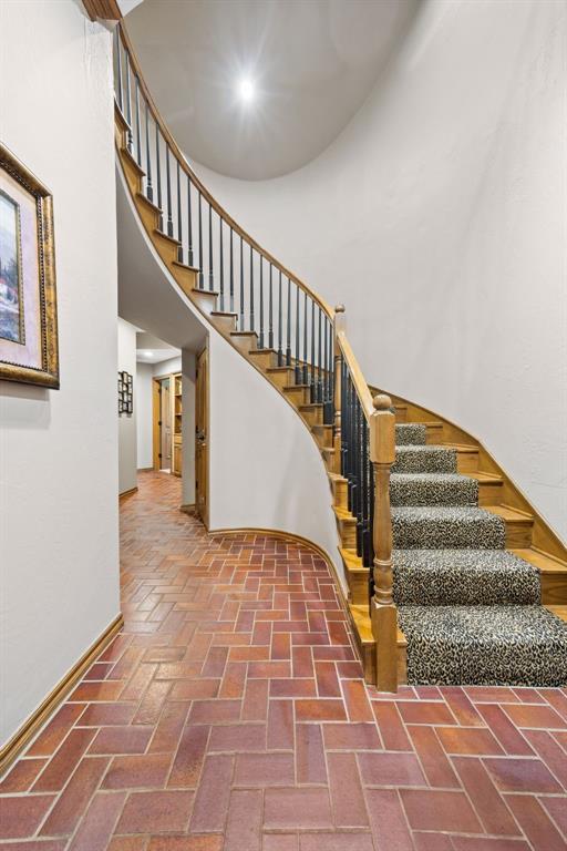 staircase with a high ceiling and brick floor