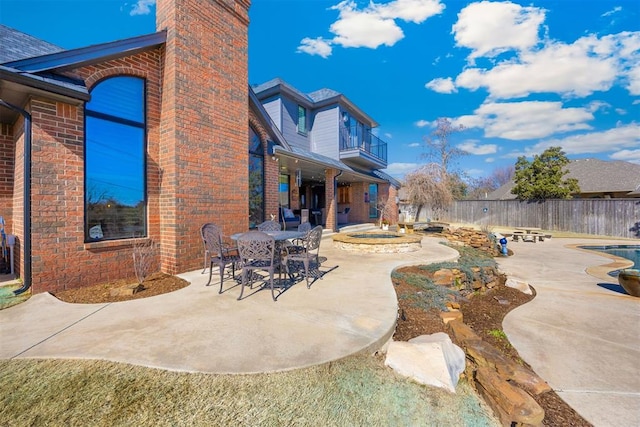 view of patio featuring a balcony, fence, a fenced in pool, and an outdoor fire pit