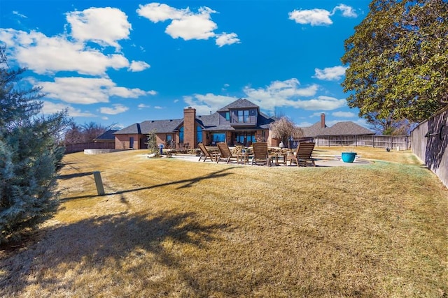 rear view of property with a patio, fence, a lawn, and a chimney