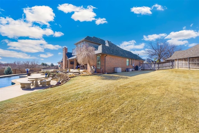 rear view of property featuring a yard, fence, brick siding, and a patio area