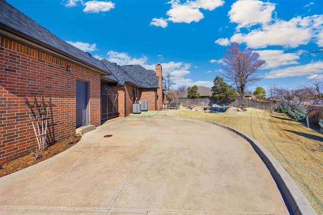 view of patio featuring concrete driveway, cooling unit, and fence