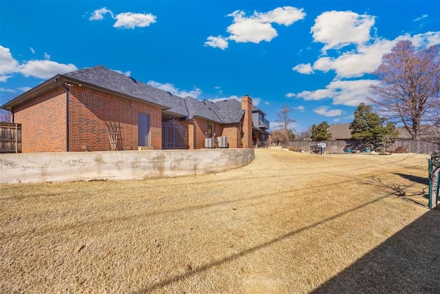 view of side of property with a yard, fence, and brick siding