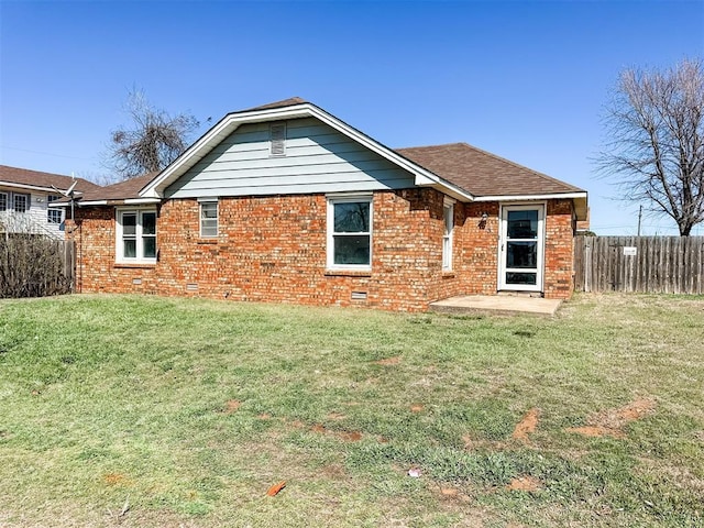 rear view of property with a patio, fence, a yard, crawl space, and brick siding