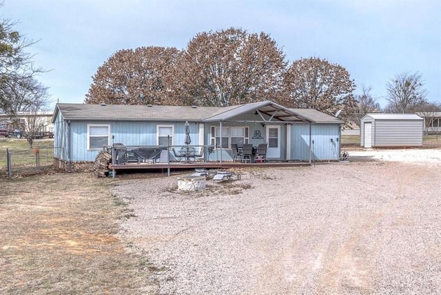 rear view of house with fence, a storage shed, a deck, an outdoor structure, and driveway