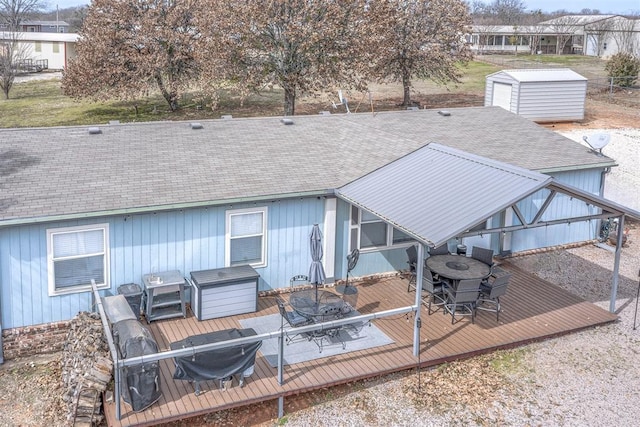 back of property with a wooden deck, outdoor dining area, an outdoor structure, and a shed