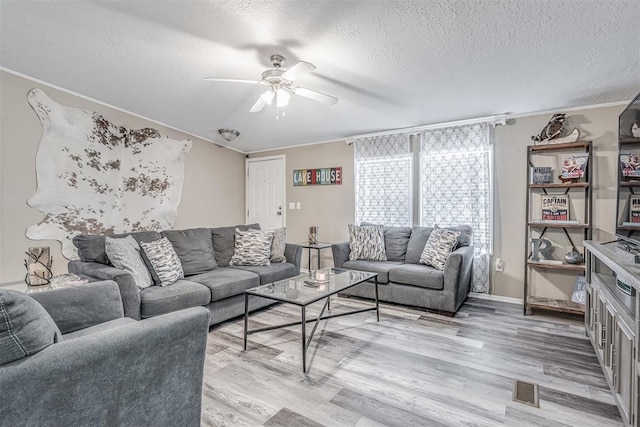 living room with visible vents, light wood-style floors, a ceiling fan, and a textured ceiling