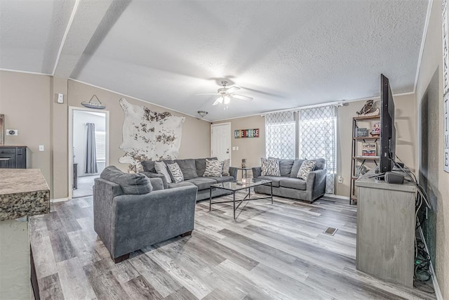 living area featuring a textured ceiling, light wood finished floors, and ceiling fan