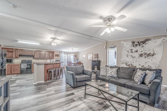 living area with a ceiling fan, light wood-type flooring, and a textured ceiling