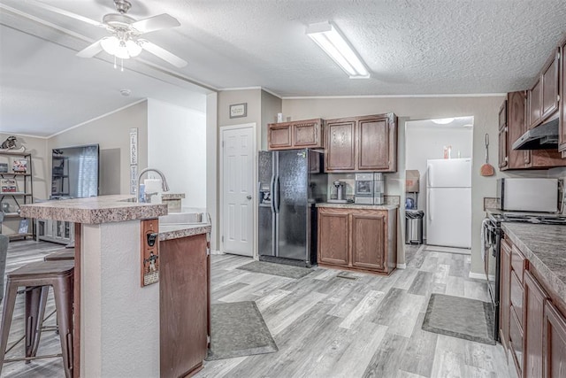 kitchen with light wood finished floors, lofted ceiling, ornamental molding, black appliances, and a kitchen breakfast bar