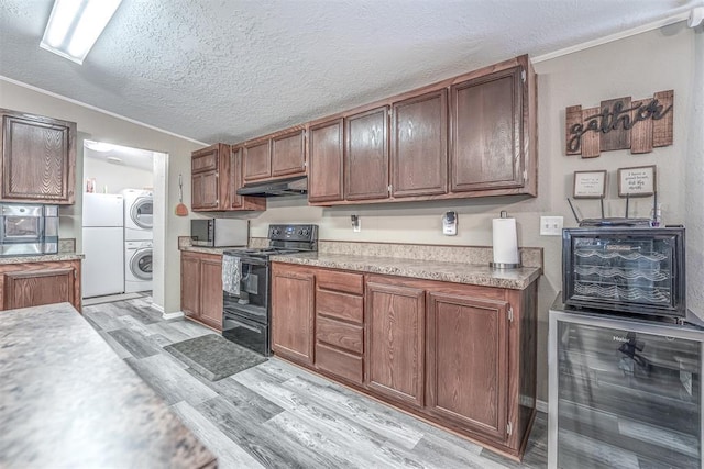 kitchen with beverage cooler, under cabinet range hood, stainless steel microwave, black range with electric cooktop, and stacked washing maching and dryer