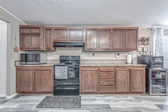 kitchen featuring light wood-type flooring, under cabinet range hood, stainless steel microwave, black / electric stove, and wine cooler