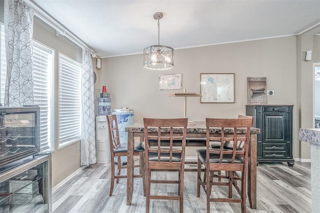 dining space featuring crown molding, a notable chandelier, wood finished floors, and baseboards