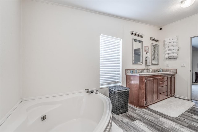 full bath with double vanity, a bath, wood finished floors, and a sink