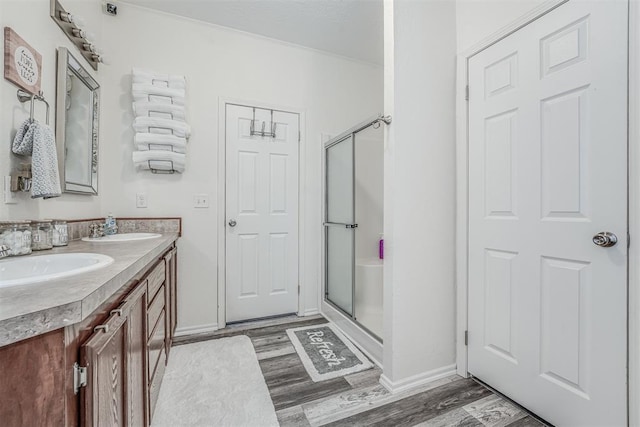 bathroom featuring a stall shower, wood finished floors, and a sink