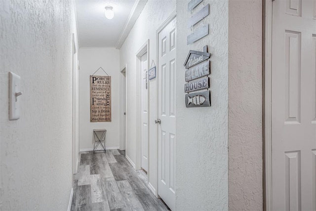 hall with wood finished floors and a textured wall