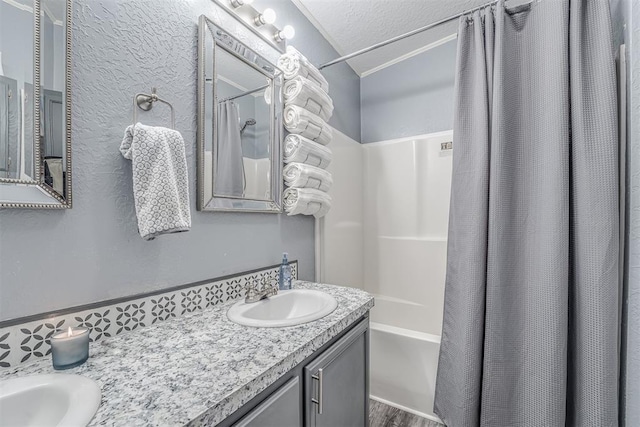 bathroom featuring a sink, a textured ceiling, shower / bath combo, and double vanity