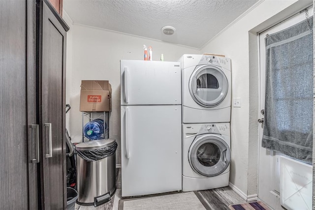 washroom featuring a textured ceiling, wood finished floors, stacked washing maching and dryer, baseboards, and laundry area