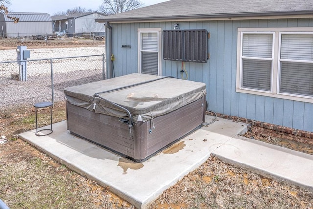 exterior space featuring gutters, a jacuzzi, fence, and roof with shingles