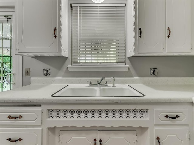 kitchen featuring white cabinets, light countertops, and a sink