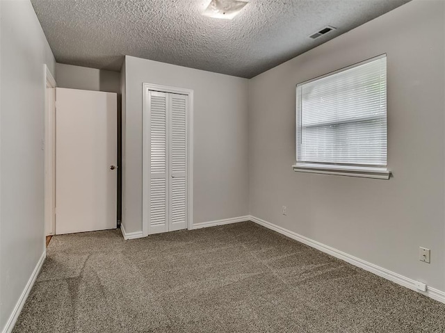 unfurnished bedroom with baseboards, visible vents, a closet, a textured ceiling, and carpet flooring