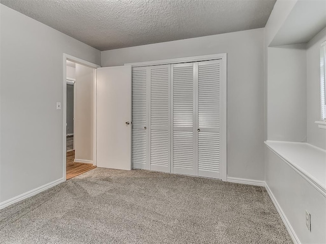 unfurnished bedroom with baseboards, a closet, carpet floors, and a textured ceiling