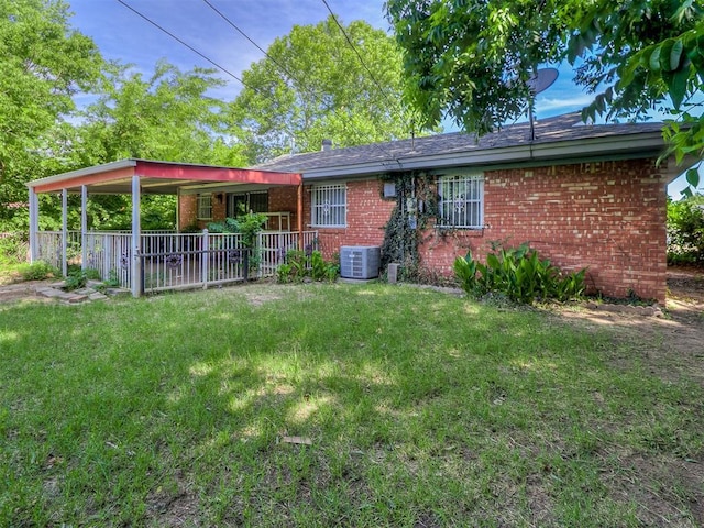 back of property featuring brick siding, cooling unit, and a yard