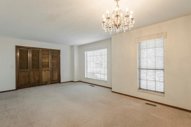 unfurnished bedroom featuring baseboards, multiple windows, a textured ceiling, and carpet flooring