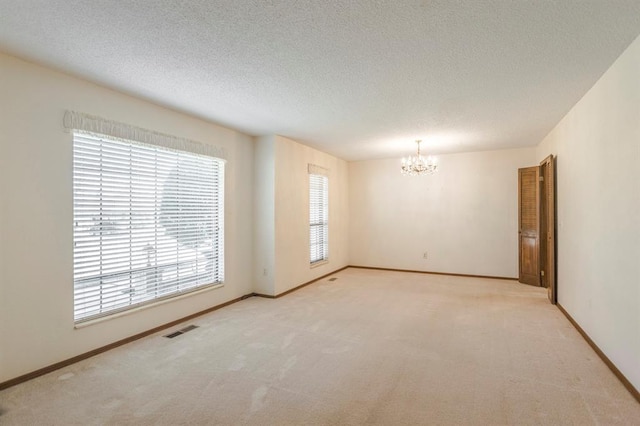 carpeted empty room featuring visible vents, baseboards, a notable chandelier, and a textured ceiling