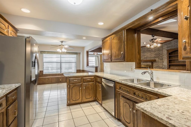 kitchen with backsplash, appliances with stainless steel finishes, a peninsula, light tile patterned flooring, and a sink