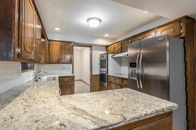 kitchen with under cabinet range hood, a sink, recessed lighting, stainless steel appliances, and decorative backsplash