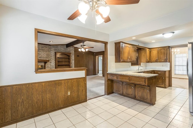 kitchen featuring wooden walls, a peninsula, beam ceiling, freestanding refrigerator, and wainscoting