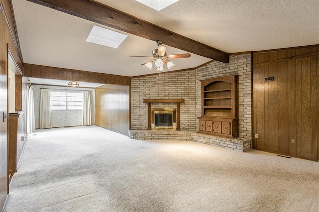 unfurnished living room featuring carpet flooring, a textured ceiling, wood walls, and a fireplace