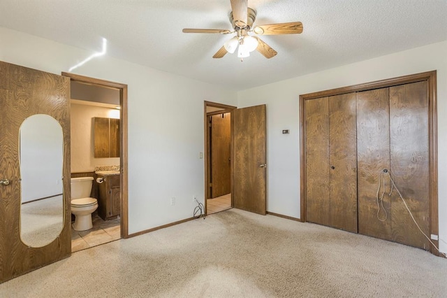 unfurnished bedroom with baseboards, carpet floors, ensuite bathroom, a closet, and a textured ceiling