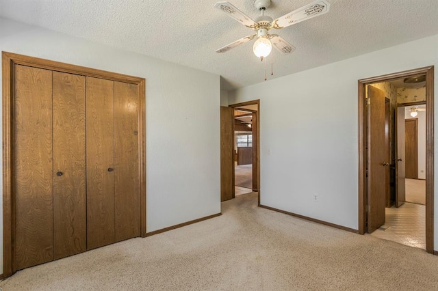 unfurnished bedroom featuring baseboards, ceiling fan, carpet, a closet, and a textured ceiling