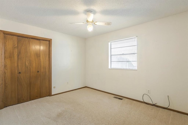 unfurnished bedroom with visible vents, carpet, a closet, and a textured ceiling