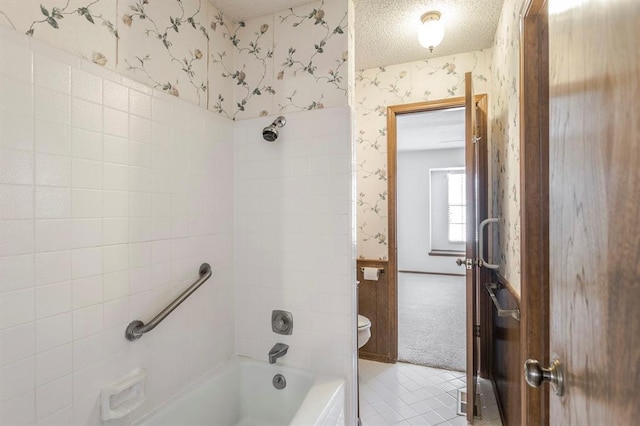 bathroom with toilet, a textured ceiling, wallpapered walls, and shower / tub combination