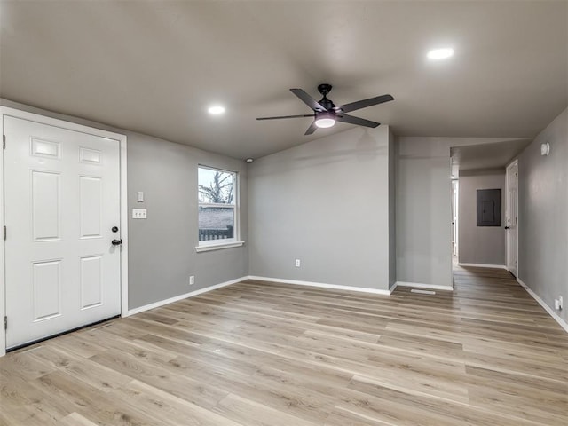 interior space featuring electric panel, light wood-style flooring, baseboards, and lofted ceiling