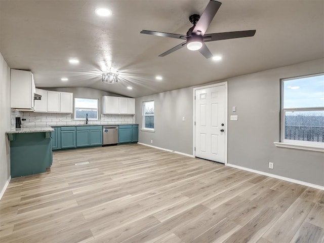 kitchen with lofted ceiling, blue cabinetry, a sink, light wood-type flooring, and backsplash