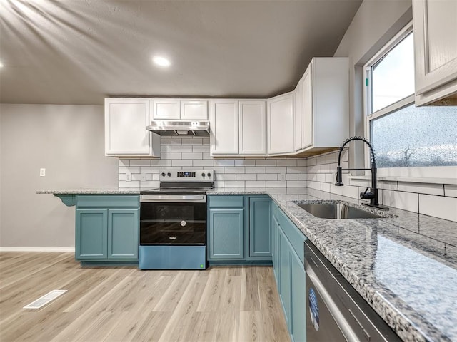 kitchen with blue cabinets, a sink, under cabinet range hood, tasteful backsplash, and stainless steel appliances