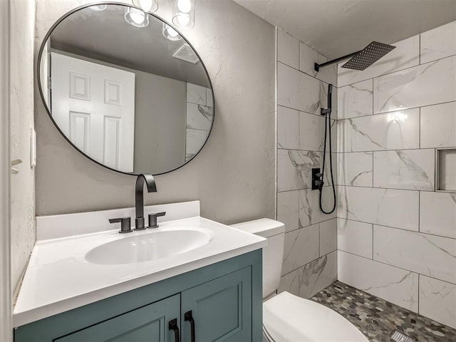 full bathroom featuring visible vents, tiled shower, toilet, and vanity