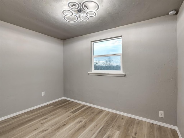 unfurnished room with baseboards, a textured ceiling, and wood finished floors